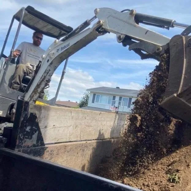 Excavatrice chargeant de la terre pendant des travaux de préparation de terrain